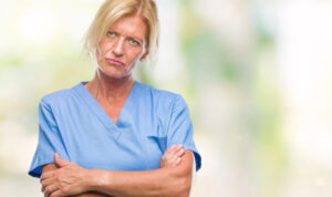 A surly nurse receptionist frowns and crosses arms