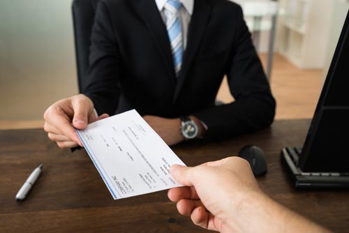 A photo of a buyer handing over a check to the seller depicting the buying of a business