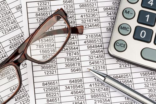A photo of a financial statement, with reading glasses, a pen, and a calculator