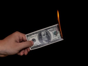 A photo of a $100 bill burning representing the disadvantages of discounts