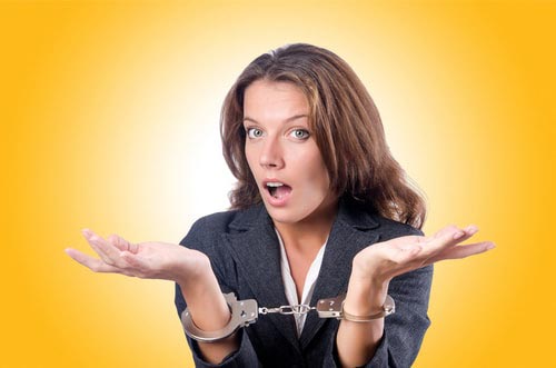 A photo of a professional woman in handcuffs depicting employee embezzlement