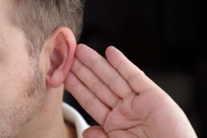 A man holds his hand to his ear to demonstrate How to Quickly Enhance Your Listening Skills
