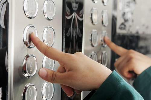 A photo of a man punching an elevator button that depicts writing an elevator pitch