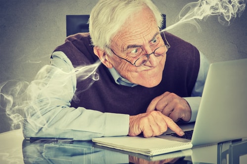 An elderly businessman looks at his laptop with steam coming out of his ears depicting 5 Legitimate Reasons to Sell Your Business