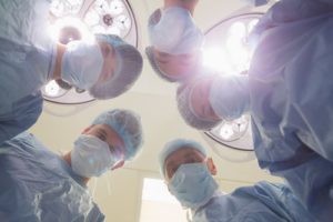 A team of surgeons and nurses look down at their patient