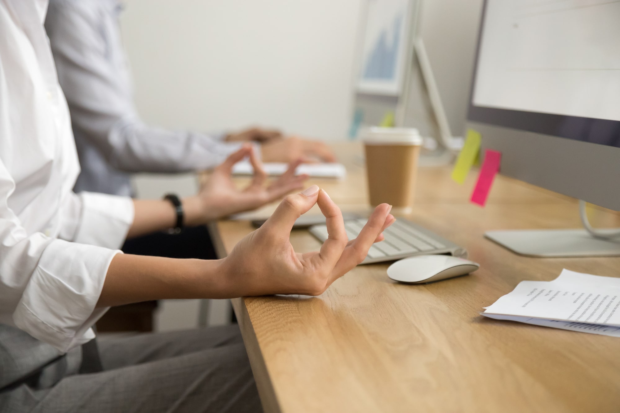 A woman leader meditates at her desk depicting the relationship between stress and productivity