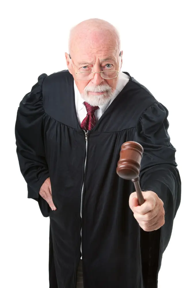 A robed, bald male judge shakes his gavel to help you identify and reject your cognitive bias in decision-making