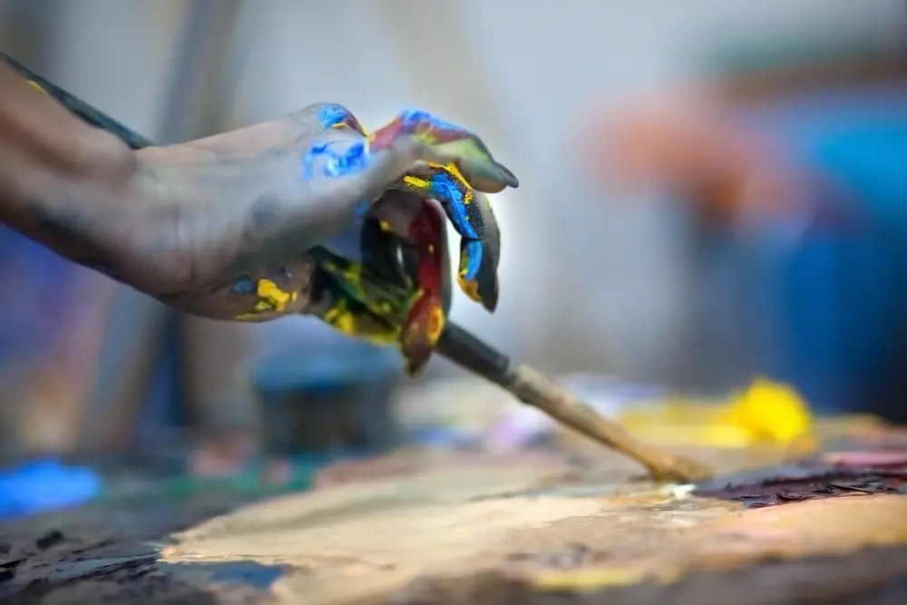 an artist's hand is mixing paint and demonstrating her way to stimulate creativity