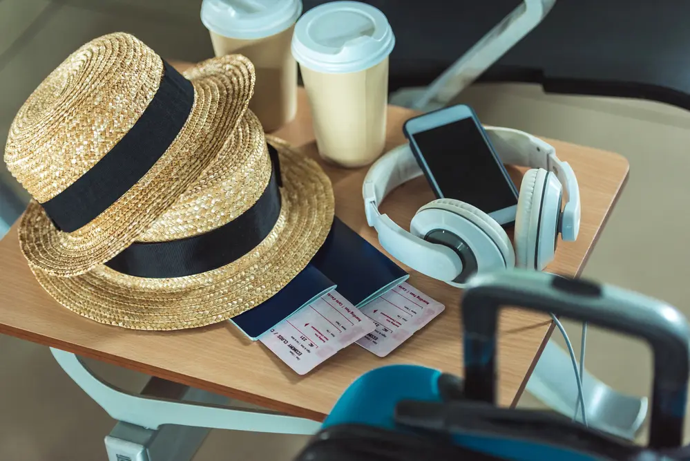 a photo of hats, headphones, passports, and drinks that show how cool it is for a small business owner's vacation