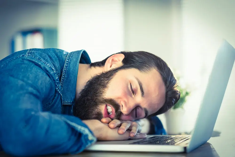 A workaholic businessman sleeping on his laptop keyboard 