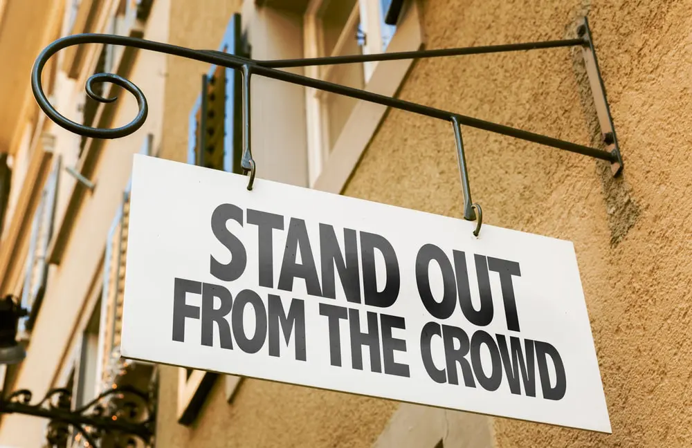 A sign reads "stand out from the crowd" and support the concept of differentiating your business from competitors