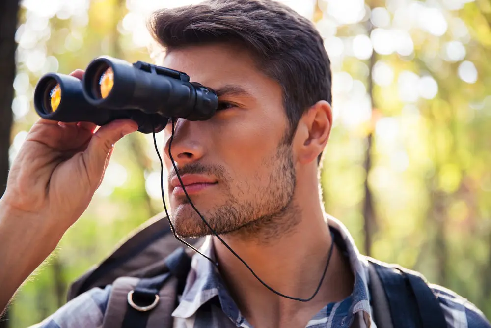 a man looks through a pair of binoculars which symbolizes how to communicate your vision to your team