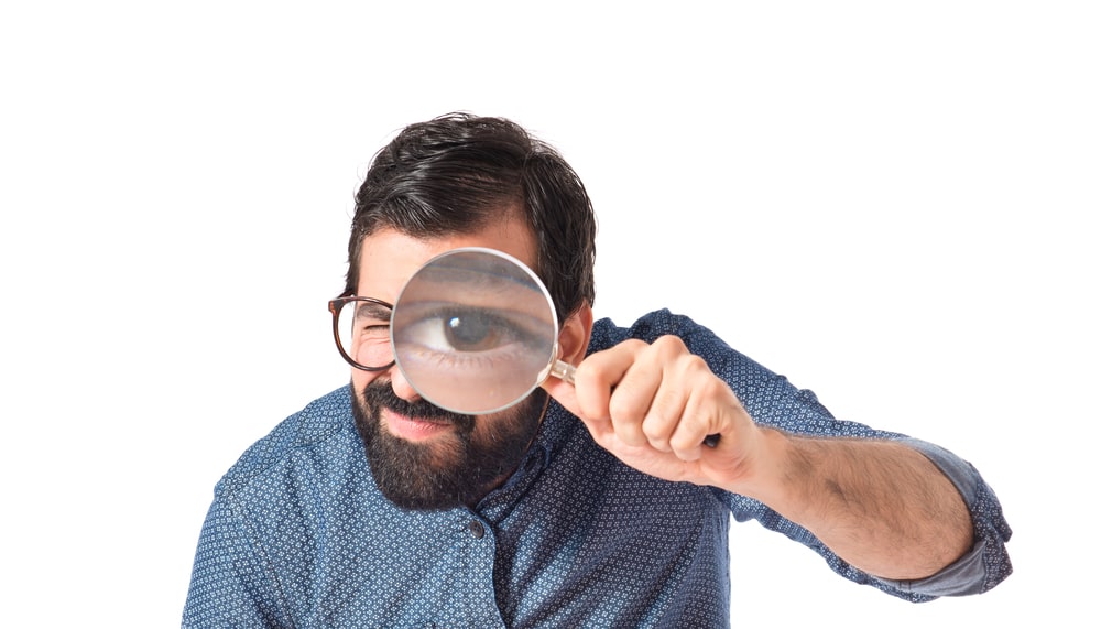 A man with a magnifying glass looking for leadership critical thinking skills