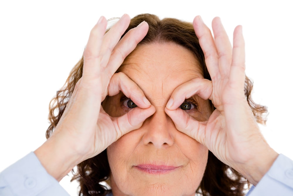 A woman looks through her fingers that symbolize how to qualify a sales prospect