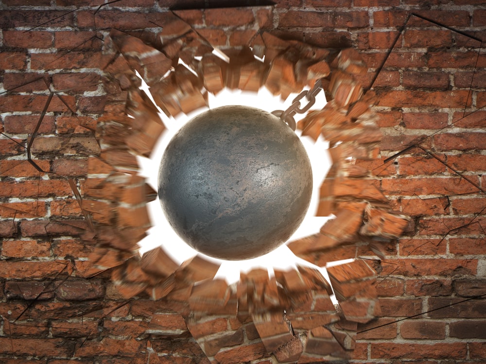 A wrecking ball blows up a brick wall symbolizing a proper reaction to competition in business