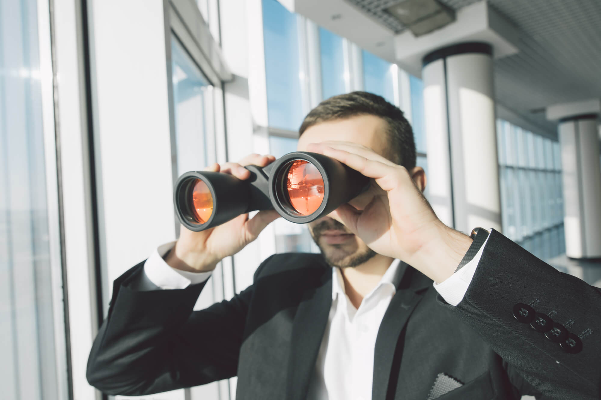 A businessman looks through binoculars for the mysterious perfect client