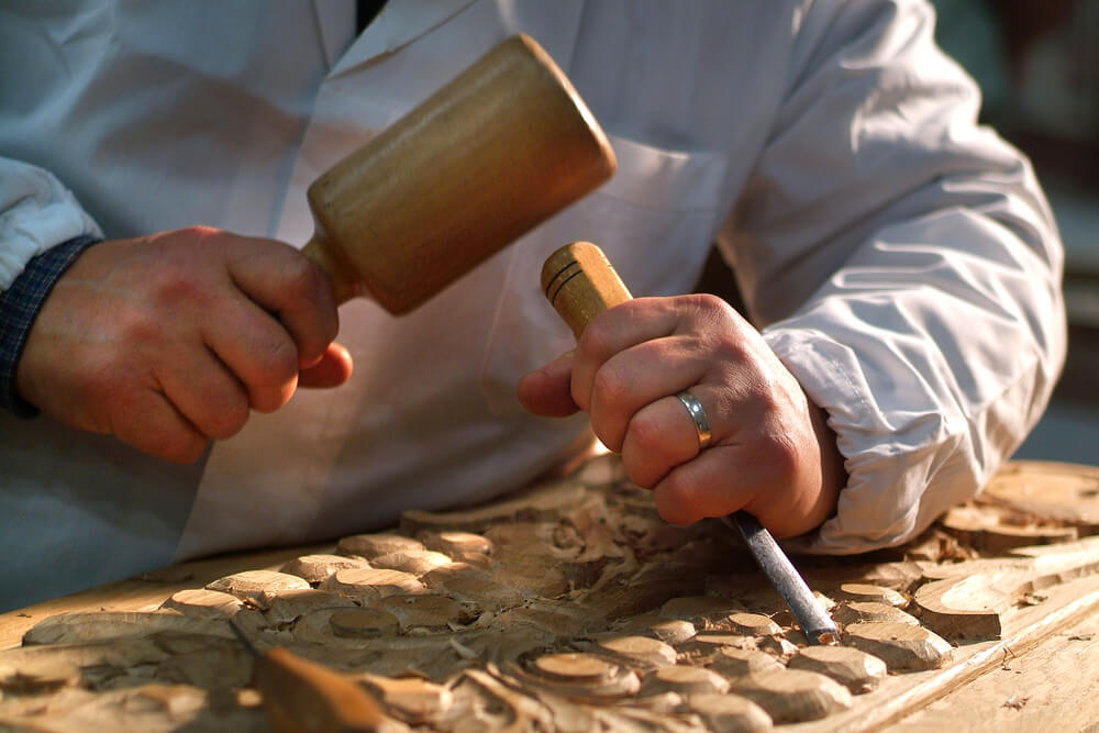 A sculptor with a chisel and hammer creates an etching in the wood just as you would craft a marketing plan.