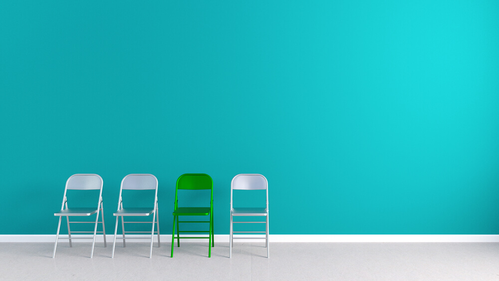 A photo of 4 chairs. Three are exactly the same and one is bright green suggesting uniqueness.