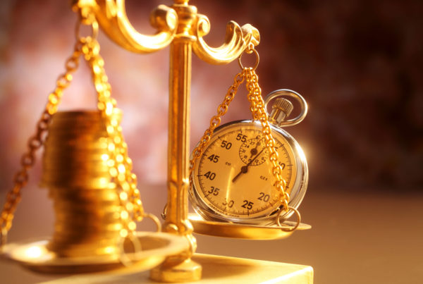 a golden scale balancing time and money by showing a pile of coins and a pocket watch