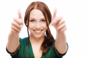 A smiling business woman gives two thumbs up displaying her positive attitude