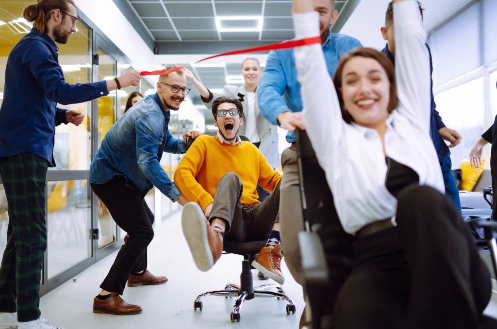 a group of employees celebrate with chair races in their office