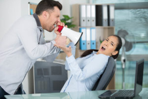 An aggressive male manager shouts through a microphone to persuade an woman employee