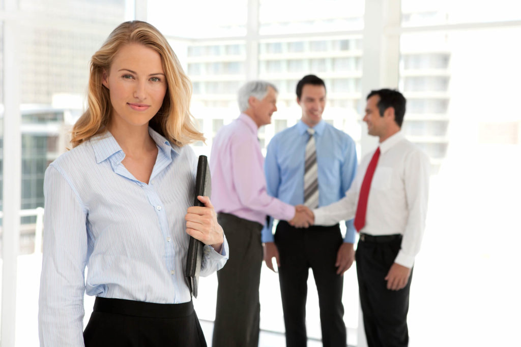 A professional woman is pictured as a sales manager standing next to sales people