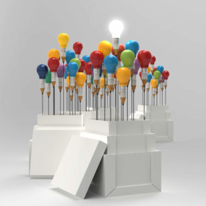 One bright white lightbulb rises above of a large collection of multicolored lightbulbs.