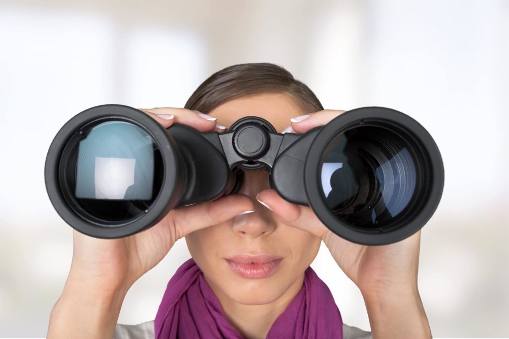 A woman looks through a pair of oversized binoculars