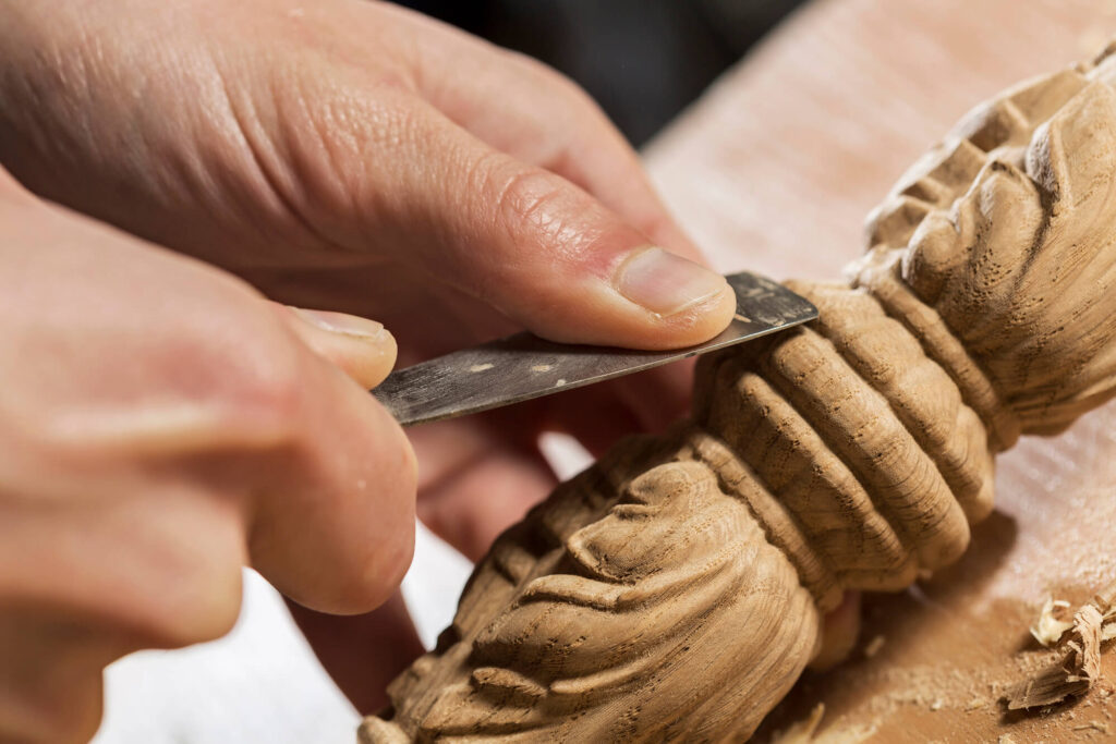 A close-up photo of a skilled carpenter carefully shaping a wooden spindle