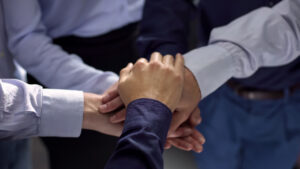 A photo of a team with all of their hands in the circle depicting a strategic partnership.
