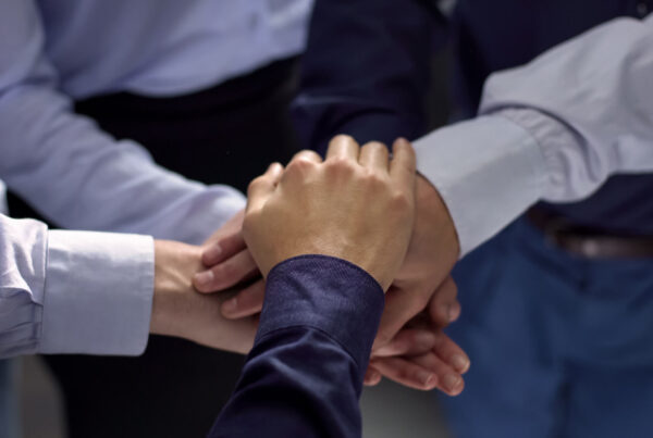 A photo of a team with all of their hands in the circle depicting a strategic partnership.