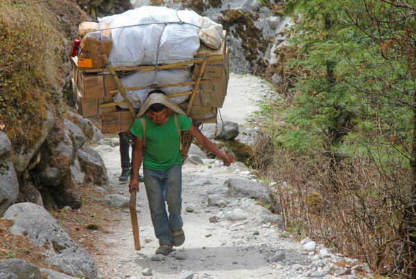 A photo of a highly motivated Sherpa carrying a large load on his back