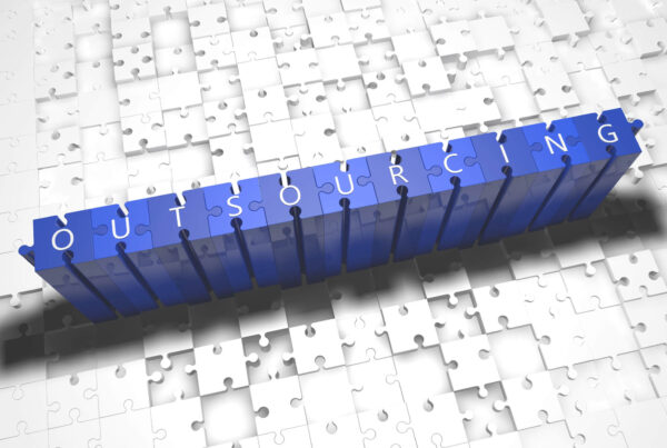 A stack of blue blocks spells the word outsourcing