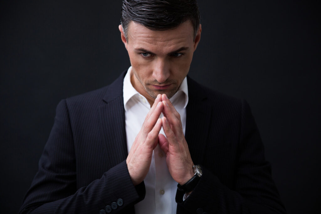 A very serious business executive creates a temple with his fingers, demonstrating executive loneliness