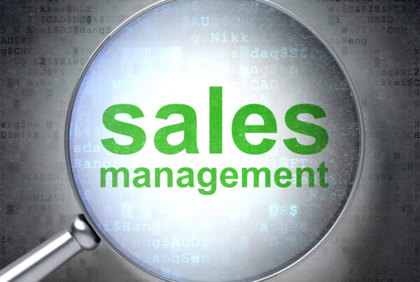 The words Sales Management are viewed through a magnifying glass