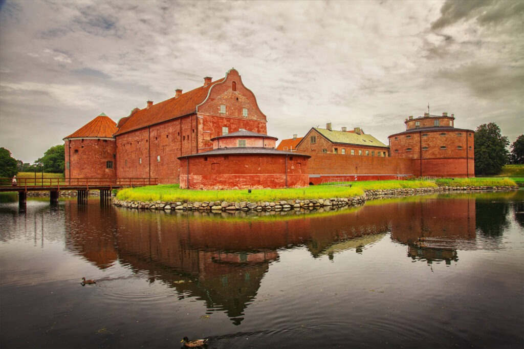 A photo of a medieval castle with a wide water moat surrounding the castle