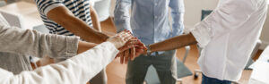 A team of workers puts their hands in a circle as a sign of unity.