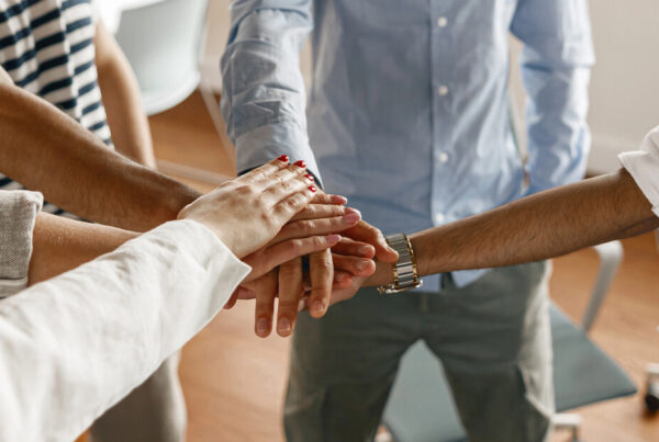 A team of workers puts their hands in a circle as a sign of unity.