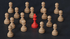 A photo of an array of tan chess pieces and one red King chess piece