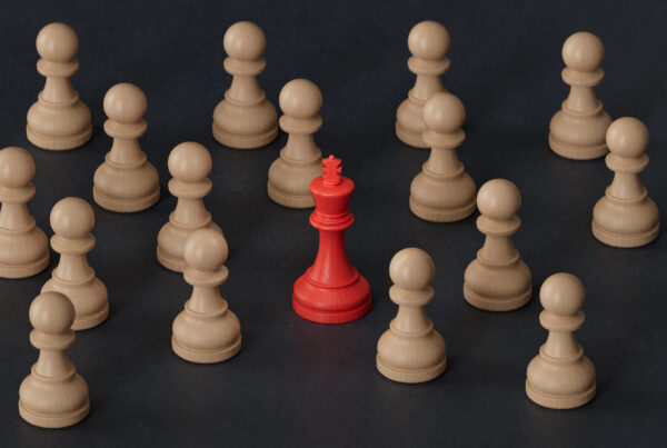 A photo of an array of tan chess pieces and one red King chess piece