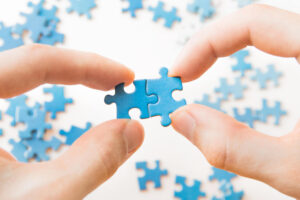 a woman's fingers hold two puzzle pieces together depicting a strategic partnership