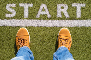 A top-down photo of a man's running shoes at the starting line of a race.