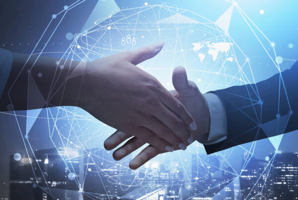 Two business people shake hands in front of an image of the globe.