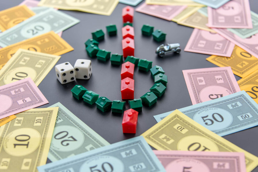 A Monopoly board is shown with scattered currency and dollar sign made up of the houses and hotel pieces