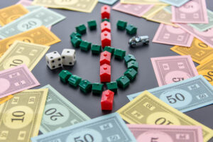 A Monopoly board is shown with scattered currency and dollar sign made up of the houses and hotel pieces