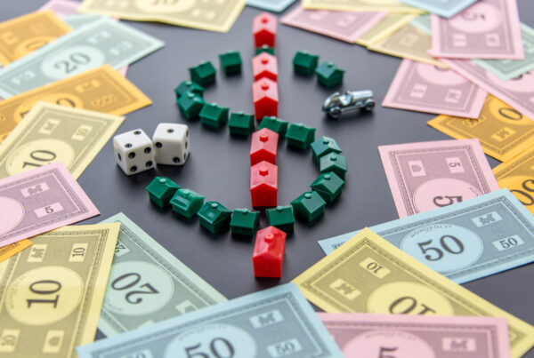 A Monopoly board is shown with scattered currency and dollar sign made up of the houses and hotel pieces