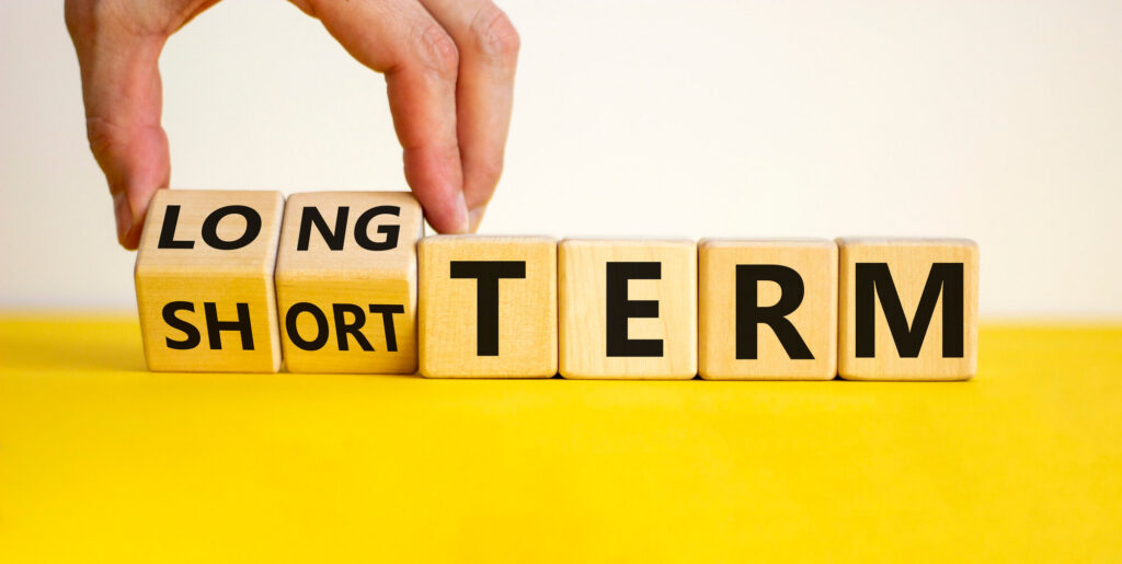 A man's hand rotates blocks spellng our short and long term goals