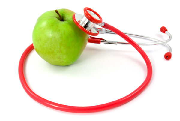 A stethoscope is on a green apple denoting an organizational check-up