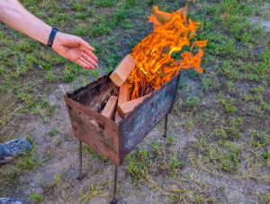 A woman feeds an outdoor fire much like a businee owner needs to feed growth